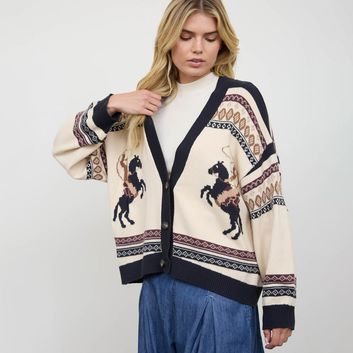 Woman modeling a three-button cardigan with horse motif and long sleeves.