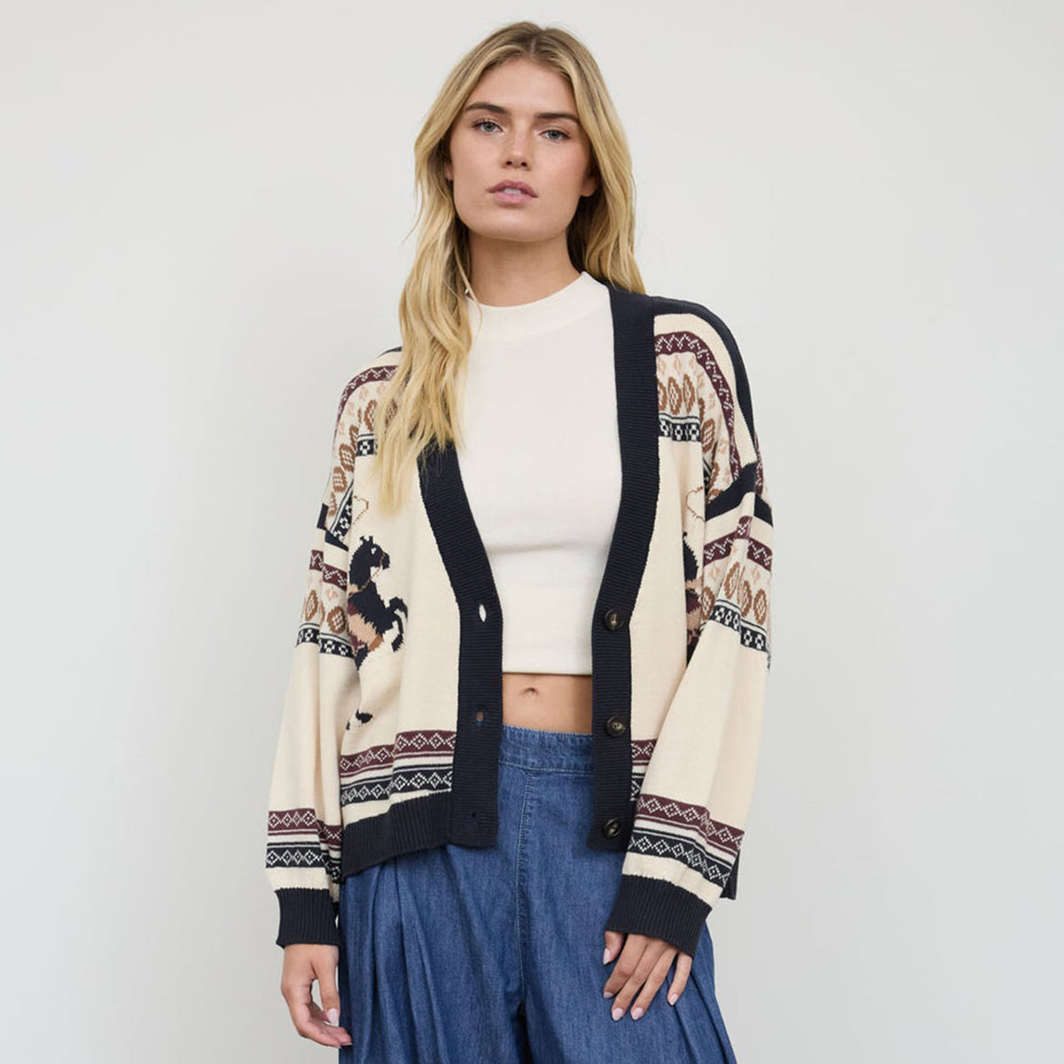 Woman modeling a three-button cardigan with horse motif and long sleeves.